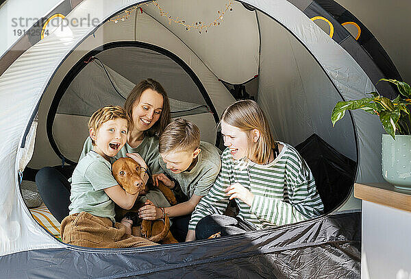 Glückliche Familie mit Vizsla-Hund  der zu Hause im Zelt spielt