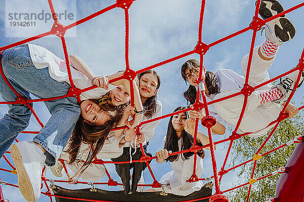 Teenage friends playing on jungle gym at park