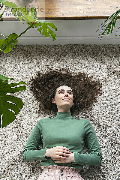 Young woman lying on rug at home
