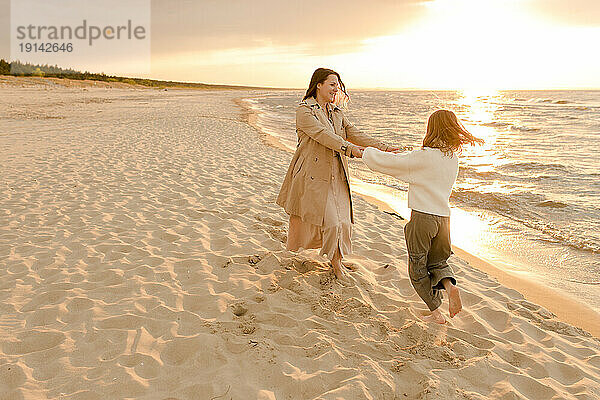 Glückliche Mutter und Tochter  die sich bei Sonnenuntergang an der Küste vergnügen