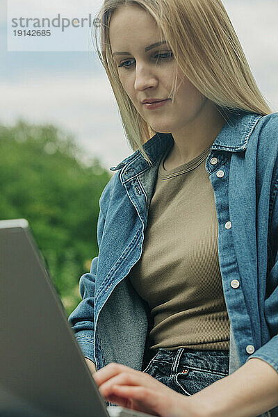 Blonde Frau benutzt Laptop im Garten