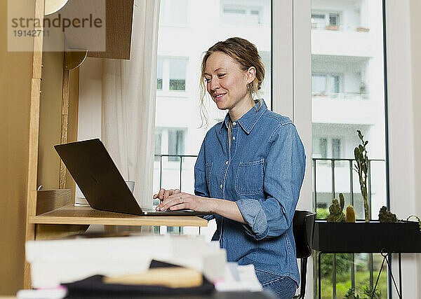 Freiberufler trägt Jeanshemd und arbeitet im Heimbüro am Laptop