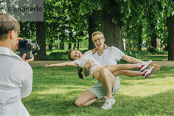 Frau fotografiert Mutter mit Tochter im Park