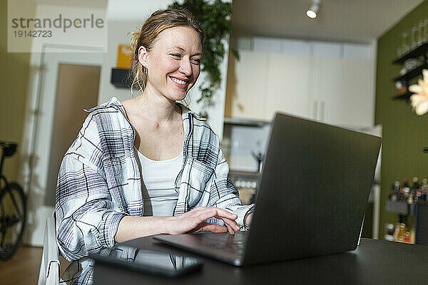 Lächelnde Geschäftsfrau  die zu Hause mit Laptop arbeitet