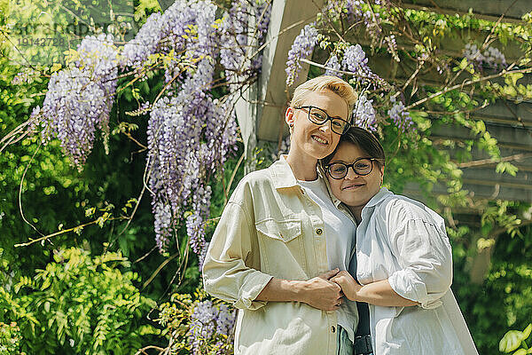Smiling lesbian couple standing by flowering plant at park