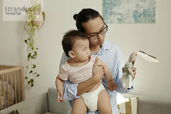 Father showing stuffed toy to daughter at home