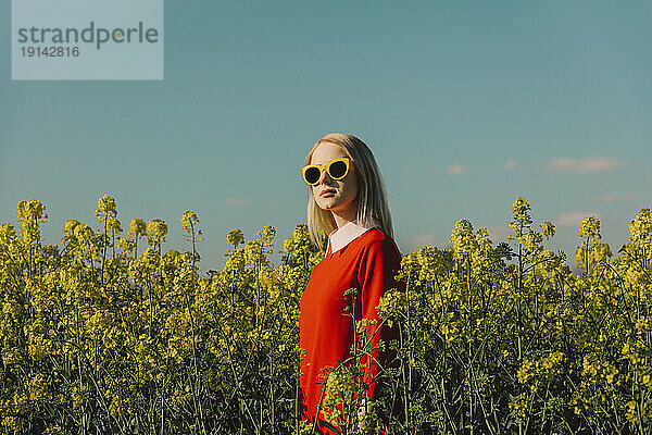 Frau mit Sonnenbrille steht im Rapsfeld