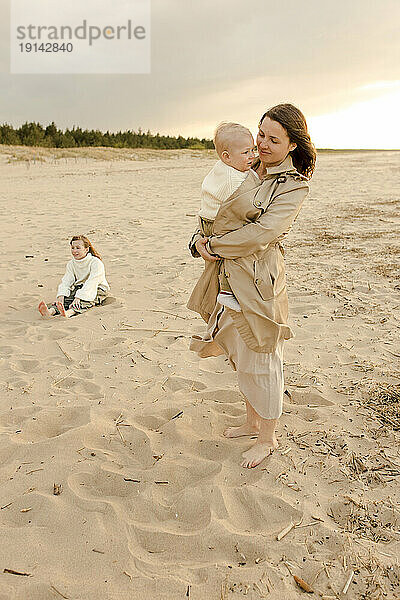 Glückliche Frau mit Sohn steht am Strand