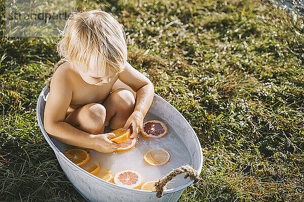 Mädchen badet mit Zitrusfrüchten in der Wanne