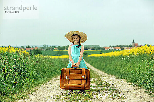 Glückliches Mädchen  das mit Vintage-Koffer steht