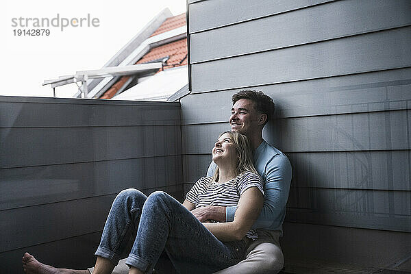 Glückliches junges Paar sitzt auf dem Balkon