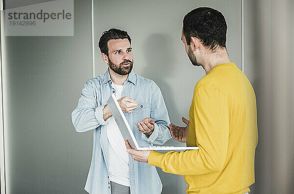 Geschäftsmann erklärt Kollegen mit Laptop im Büro