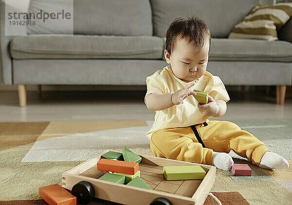Girl playing with toy blocks sitting at home