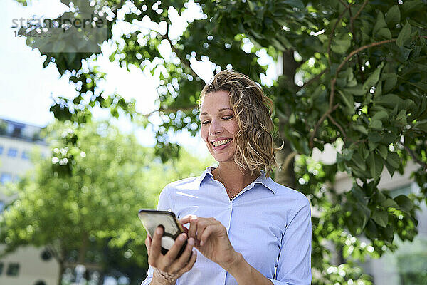 Lächelnde Frau  die Textnachrichten über das Smartphone sendet