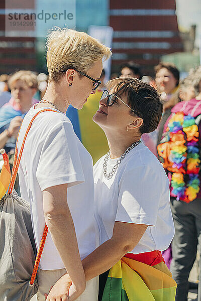 Liebevolle Lesben stehen und umarmen sich bei der Gay-Pride-Veranstaltung