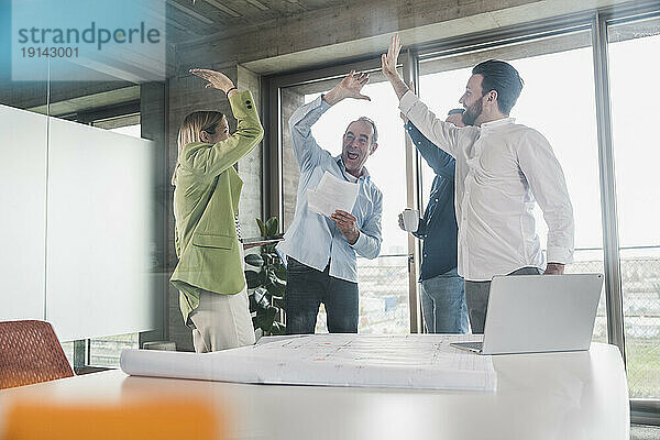 Happy business colleagues giving high-five in office