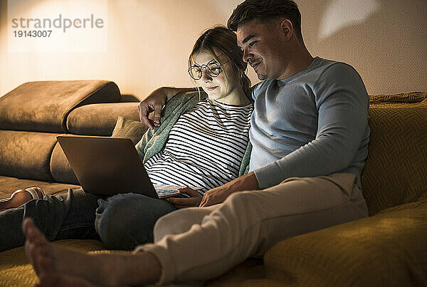 Lächelndes junges Paar  das zu Hause gemeinsam einen Laptop benutzt