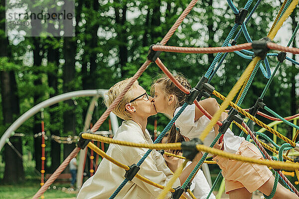 Mutter küsst Tochter auf Spielplatz