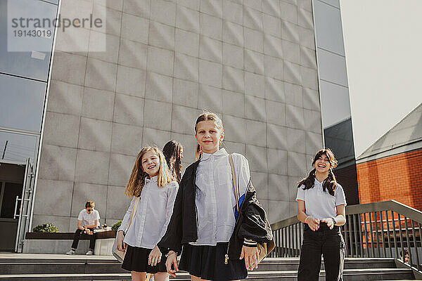 Schoolgirls spending leisure time standing in front of school building