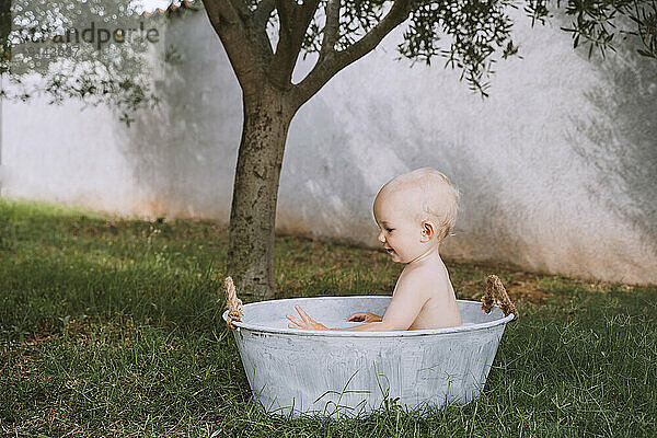 Kleiner Junge badet in Wanne im Hinterhof