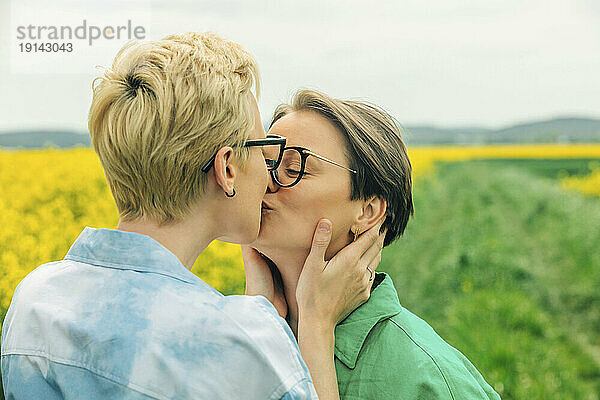 Liebevolles lesbisches Paar küsst sich im Rapsfeld