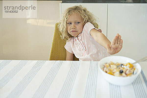 Girl refusing breakfast at table