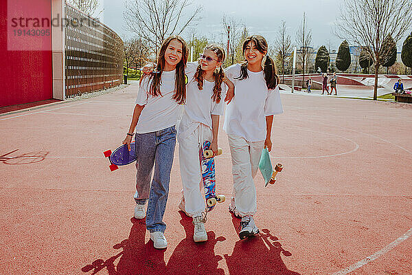 Teenage friends with skateboard walking at playground
