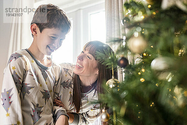 Glückliche Mutter mit Sohn  die zu Hause vor dem Weihnachtsbaum steht