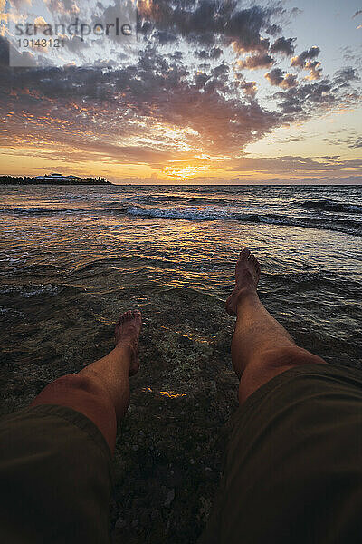 Junger Mann entspannt sich bei Sonnenaufgang am Strand