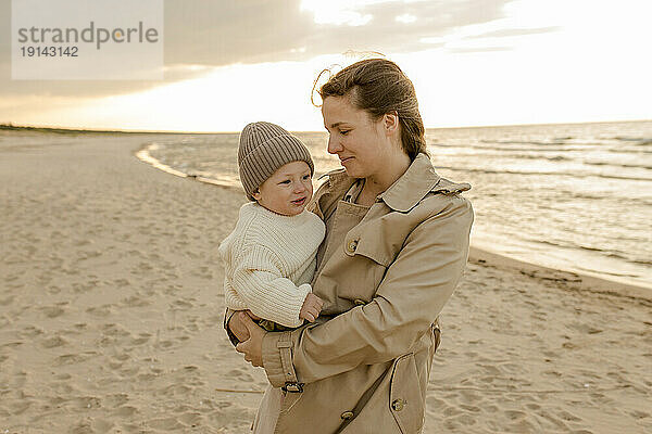 Lächelnde Frau steht mit Sohn am Strand