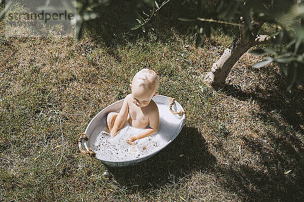 Kleinkind badet in Wanne im Hinterhof