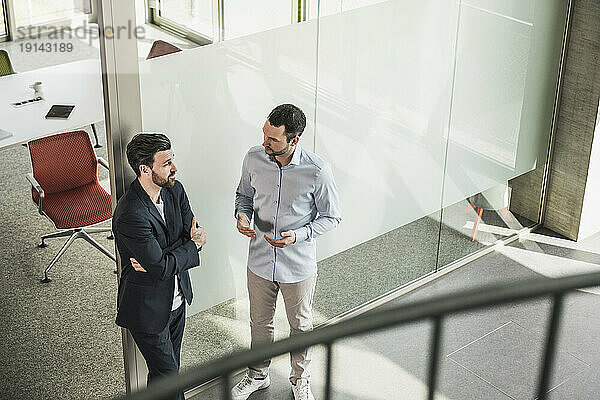 Geschäftskollegen diskutieren durch Glastür im Büro