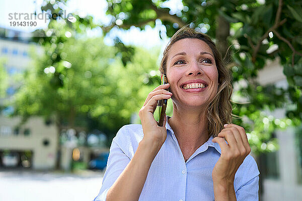 Glückliche Frau  die über ihr Smartphone spricht