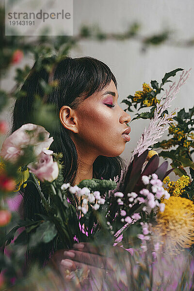 Junge Frau mit geschlossenen Augen inmitten bunter Blumen