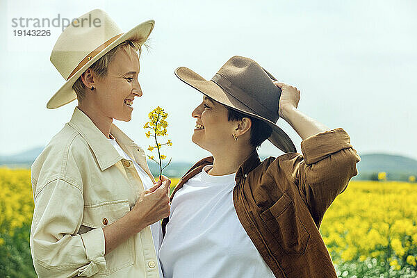 Glückliches lesbisches Paar mit Cowboyhut auf dem Feld