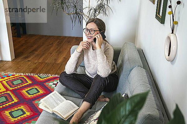 Glückliche reife Frau  die zu Hause mit dem Smartphone spricht