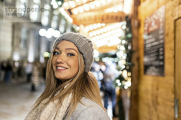 Glückliche junge Frau mit Strickmütze auf dem Weihnachtsmarkt