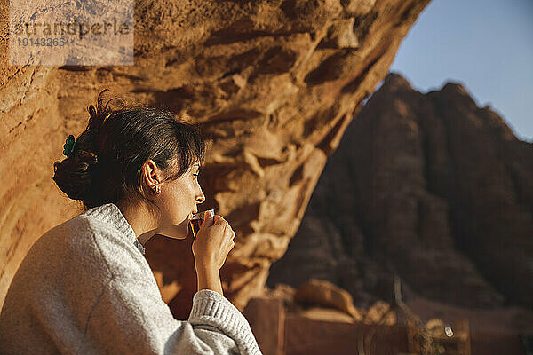 Junge Frau trinkt eine Tasse Tee und blickt auf die Wüste