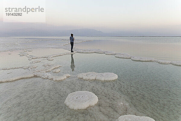 Junge Frau steht auf Salzformationen im Toten Meer