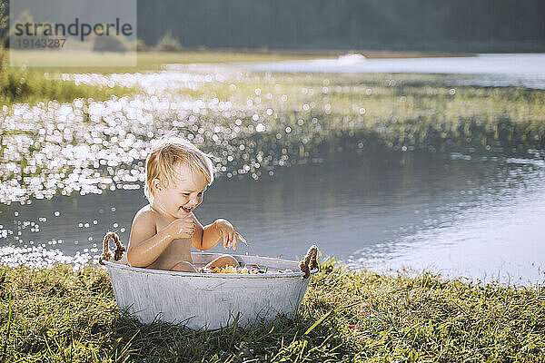 Glückliches Mädchen genießt das Bad in der Wanne am See