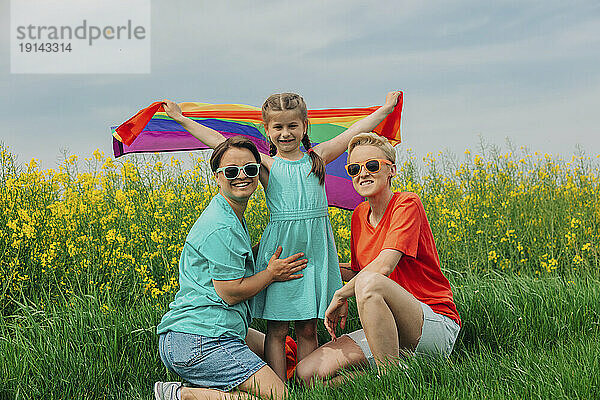 Glückliche lesbische Mütter mit Tochter  die Regenbogenfahne hält