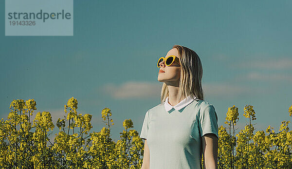 Blonde Frau mit Sonnenbrille im Rapsfeld