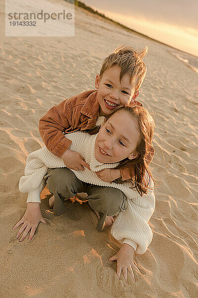 Glücklicher Junge mit Schwester  der am Strand genießt