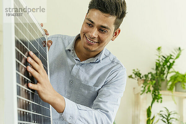 Lächelnder Geschäftsmann zeigt Solarpanel im Büro