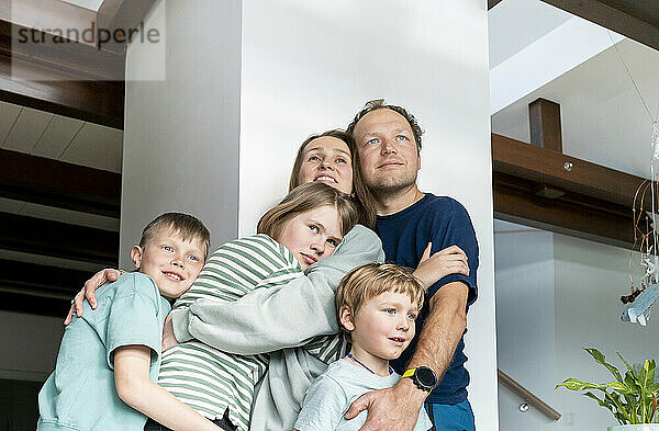 Glückliche Familie  die sich zu Hause an der Säule umarmt
