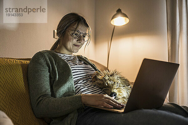 Lächelnde junge Frau  die zu Hause einen Laptop benutzt