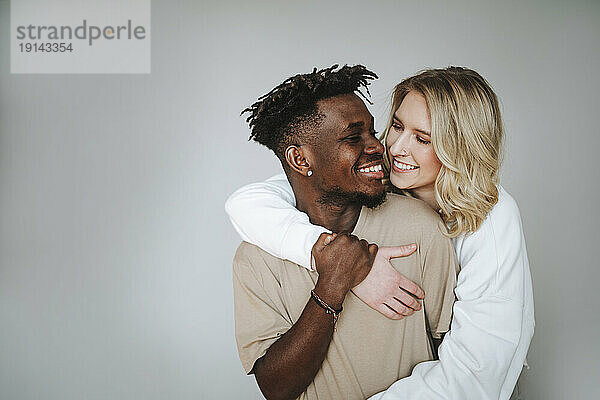 Smiling young couple embracing against gray background