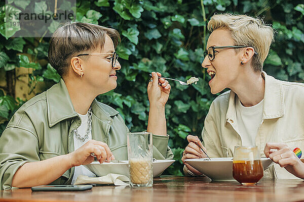 Glückliches lesbisches Paar beim gemeinsamen Essen im Café