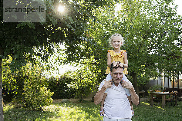 Vater trägt Tochter auf Schultern im Hinterhof