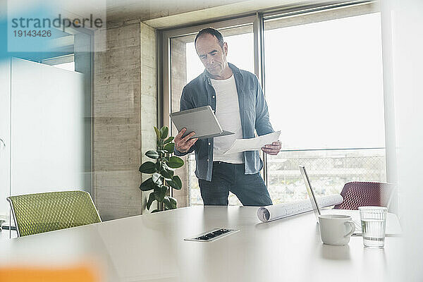 Geschäftsmann schaut im Büro auf Tablet-PC